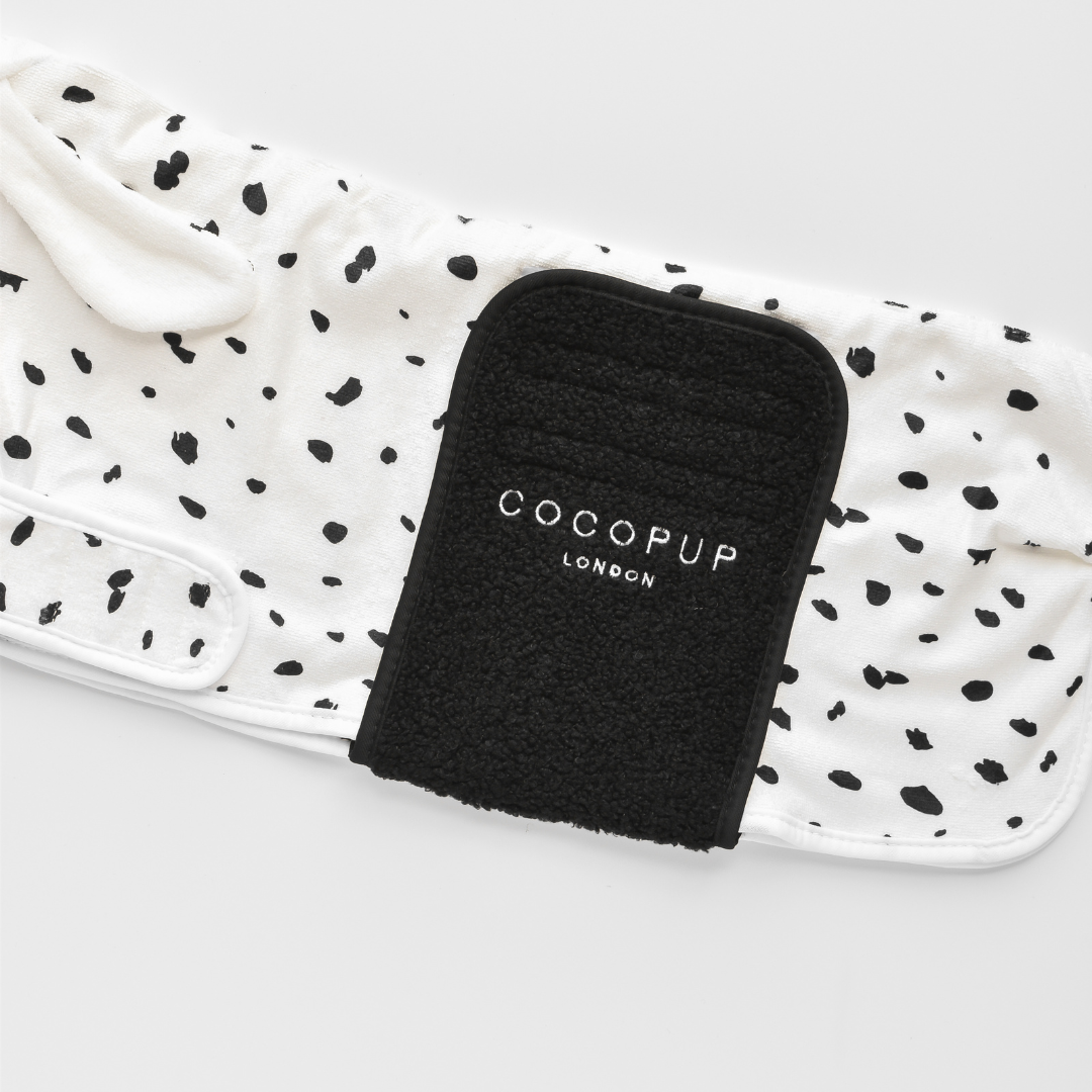 A black Cocopup London dog harness is placed on a white surface next to a white leash adorned with black spots, evoking the charm of Cocopup London's Dalmatian Drying Robe.