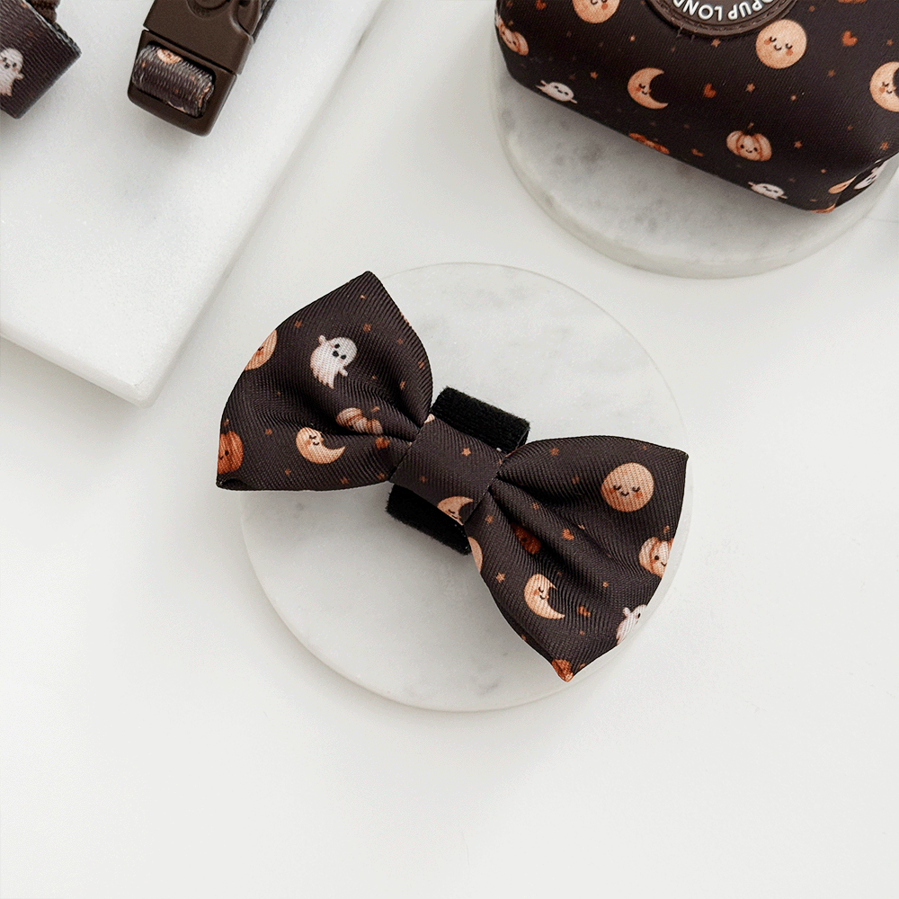 Brown dog bow tie with cute Halloween print featuring pumpkins, ghosts, and moons.