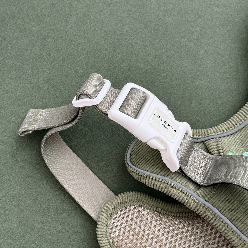 Dog harness in green corduroy material, with embroidered dinosaur design.