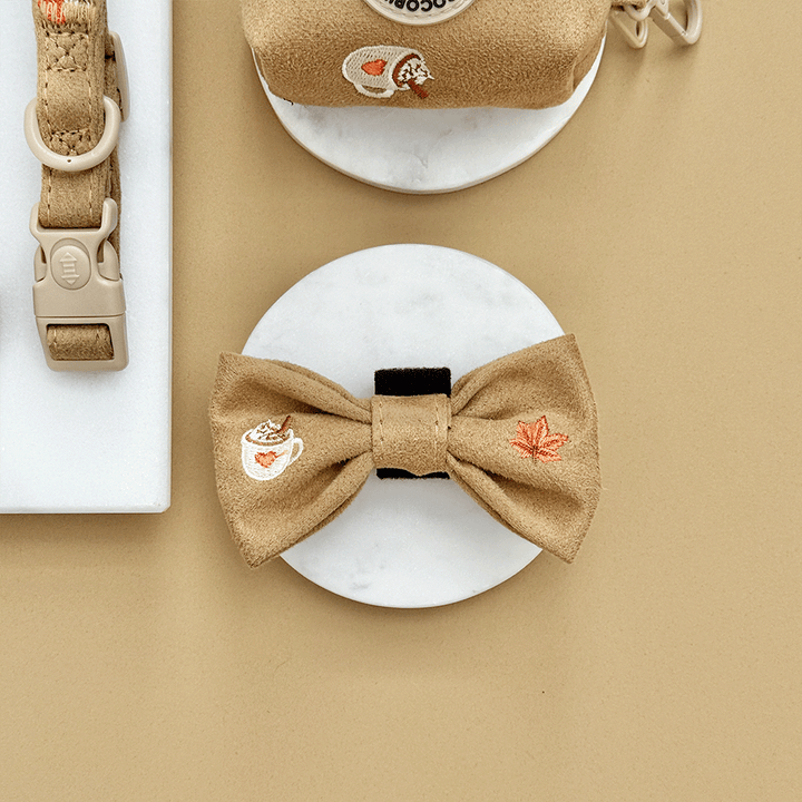 Brown dog bow tie with autumnal-themed embroidery of pumpkins, leaves, a coffee cup, and mushrooms.