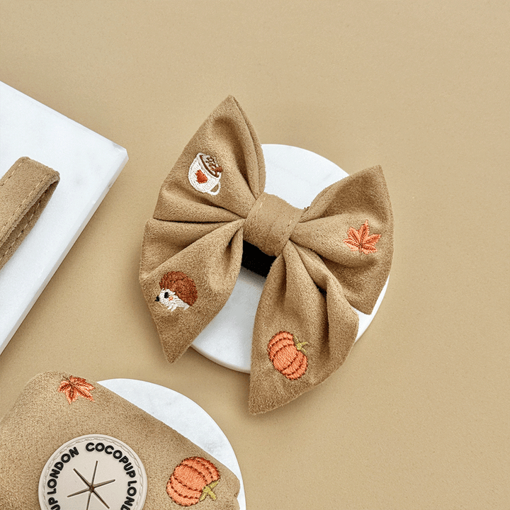 Brown dog sailor bow tie, with autumnal-themed embroidery of pumpkins, leaves, a coffee cup, and mushrooms.