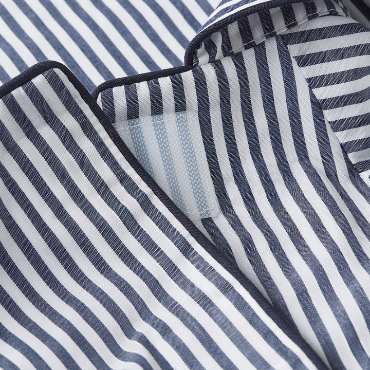 Close-up of a striped fabric garment, likely pajama or shirt material, with navy blue and white vertical stripes and a visible hook-and-loop closure.