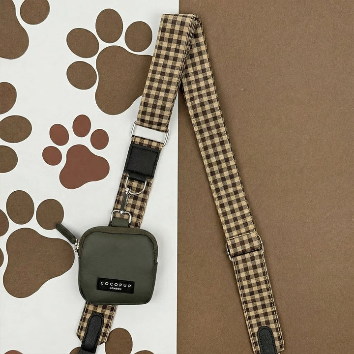 Mocha Cocopup London dog walking bag with olive treat pouch on a paw print background.