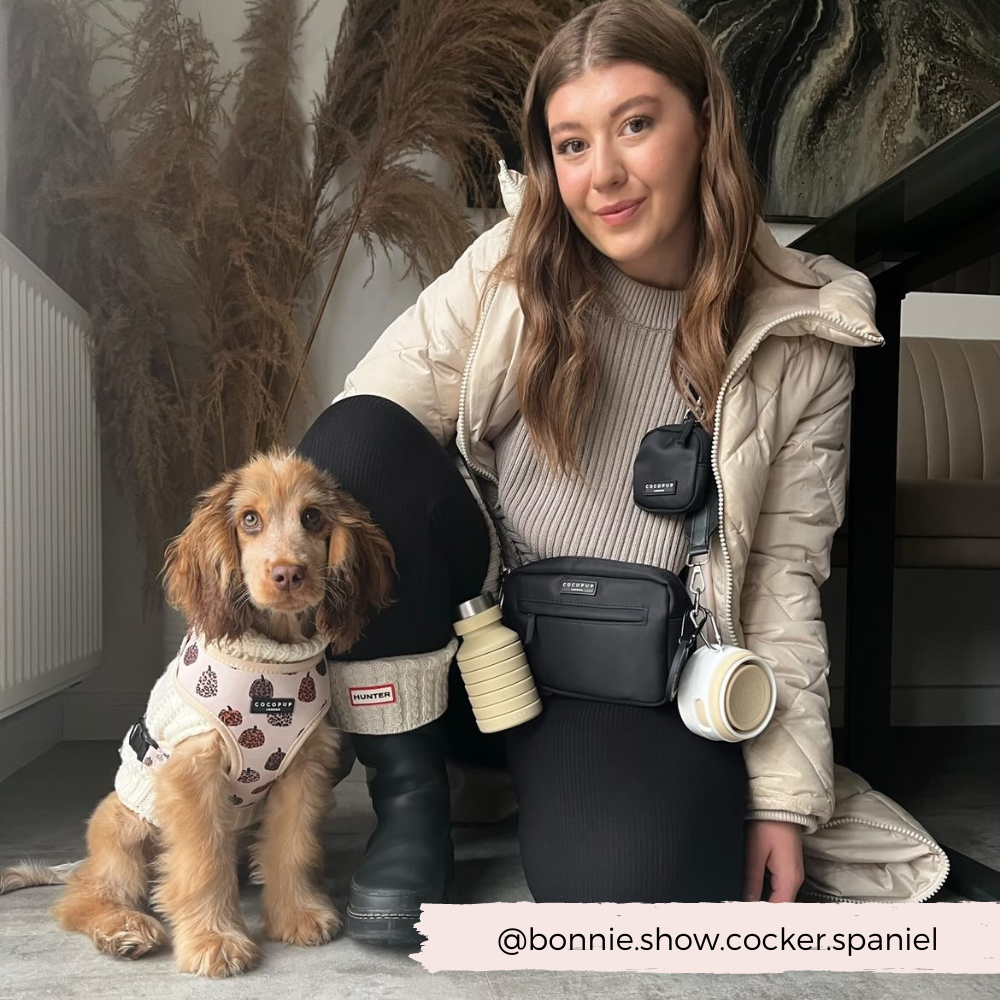 Model displaying how the Plain Nude with White Lid Collapsible Silicone Travel Coffee Cup can be attached to the Cocopup Dog Walking Bag.